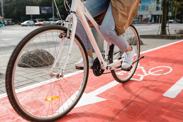 traffic, city transport and people concept - close up of woman cycling along red bike lane with signs of bicycles and two way arrows on street