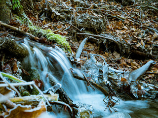A small waterfall on a stream in the forest and in winter