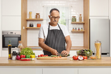Mature man cutting vegetables and preparing a salad