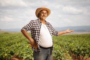 Smiling mature farmer showing a grapevine field