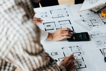 Close up of hands working brainstorming and measuring for cost estimating on paperworks and floor...