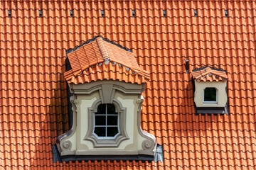 Small mezzanine with a figured window on a red tiled roof in the Czech city of Prague. From the Window of the World series.