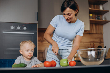 Woman with son at the kitchen preparing salad