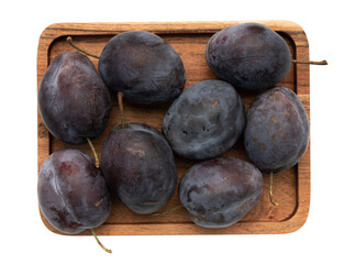 ripe plums on wooden plate isolated on white background, fresh fruits close-up