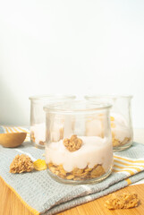 cereal, granola with yougurt in a glass, kitchen towel, wood top 