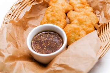 Breaded chicken fillet with sauce. Served in a wicker basket on craft paper.
