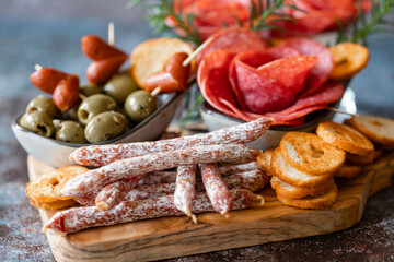 Cutting board with ham, salami, cracker and olives on a wooden board.