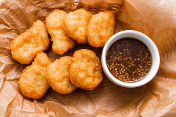 Breaded chicken fillet with sauce. Served in a wicker basket on craft paper.