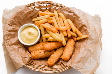 Breaded cheddar cheese sticks with french fries and sauce. Served in a wicker basket on craft paper.