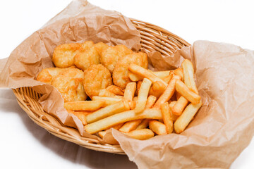 Breaded chicken fillet and french fries. Served in a wicker basket on craft paper.