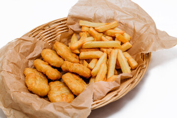 Breaded chicken fillet and french fries. Served in a wicker basket on craft paper.