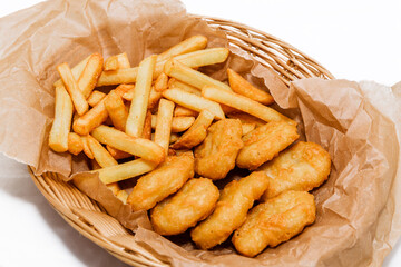 Breaded chicken fillet and french fries. Served in a wicker basket on craft paper.