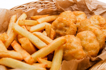 Breaded chicken fillet and french fries. Served in a wicker basket on craft paper.