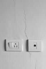 Sockets and switches on a cracked wall. Vertical photo.