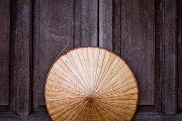 Sombrero vietnamita de paja colgado en ventana de madera oscura