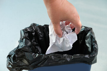 woman puts wrinkled paper in a recycling bin, close-up hands, concept of household waste disposal,...