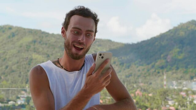 A young man emotionally tells the interlocutor about his whereabouts, inspired by the beautiful nature around, when communicating via video link. Concept of online communication. Far connected people