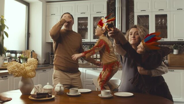 Tilting up slow motion of three noisy children running into kitchen, fighting with mother and father for chocolate cake at daytime