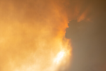 Cloud of smoke from large forest fire passing in front of sun.