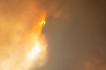 Cloud of smoke from large forest fire passing in front of sun.