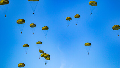 Military parachutist paratroopers parachute jumping out of a air force planes on a clear blue sky day with the moon.
