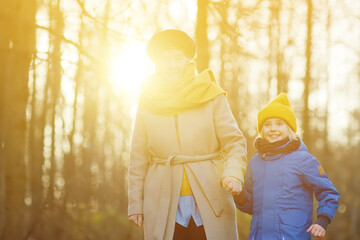 Little grandson and elderly grandmother during walking in autumn park. Friendship granny and...