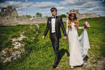 The bride and groom with a wedding bouquet in hands on the nature. Portrait of an attractive couple...