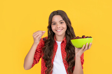 cheerful teen girl hold cherry bowl on yellow background