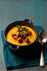 Pumpkin puree with fried onions, crackers and parsley in a ceramic blue bowl