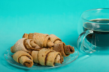 Rolls with cinnamon. Croissants with cinnamon. They lie on a saucer. There is a cup of coffee next...