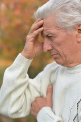 Close up portrait of older man in autumn park 