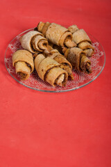 Croissants with cinnamon. Rolls with cinnamon. They lie on a saucer. The background is pink. Shot close-up.