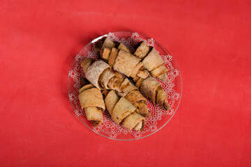 Croissants with cinnamon. Rolls with cinnamon. They lie on a saucer. The background is pink. Shot close-up.