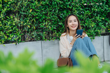 Beautiful Asian woman listening favourite music on headphones from mobile phone, Happiness relaxation summer in park with music riding bicycle in green park.