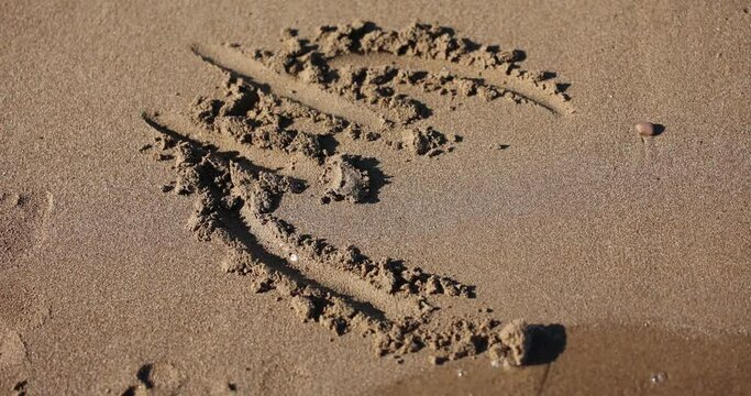 Euro symbol written on brown sand of low tide beach