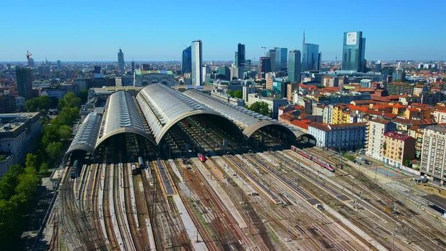 Aerial view of the station where trains arrive. An old arched structure made of metal and glass above the station poles. Tourism. Transport. Skyline with tall buildings. Italy, Milan, 09.2022
