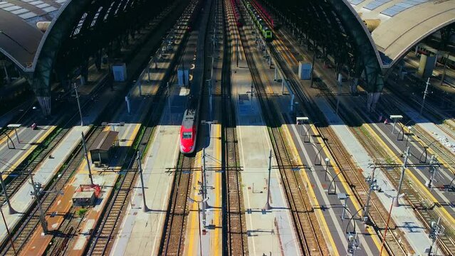 Aerial view of the station where trains arrive. An old arched structure made of metal and glass above the station poles. Tourism. Transport. Skyline with tall buildings. Italy, Milan, 09.2022