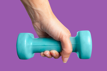 Female hand holding a dumbbell on purple background