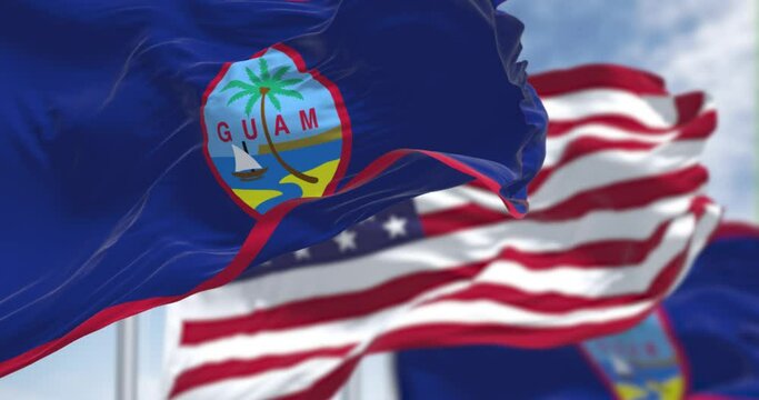 Flags of Guam waving in the wind with the US flag on a clear day