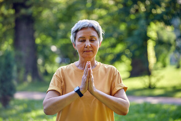 Older active Asian woman do meditation practice outdoors