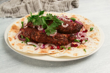 Lula kebab, on lavash, with red onion, pomegranate, and sumac, top view, close-up, horizontal, no...