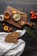 Camembert cheese is round, grilled, poured with golden honey on a wooden cutting board. Soft selective focus, black background.Space for copying. Healthy eating. Vertical photo.