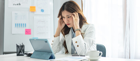 Businesswoman is feeling stress and headache while reading marketing plan report on tablet to analysis investment and planning to management project of new business in modern office