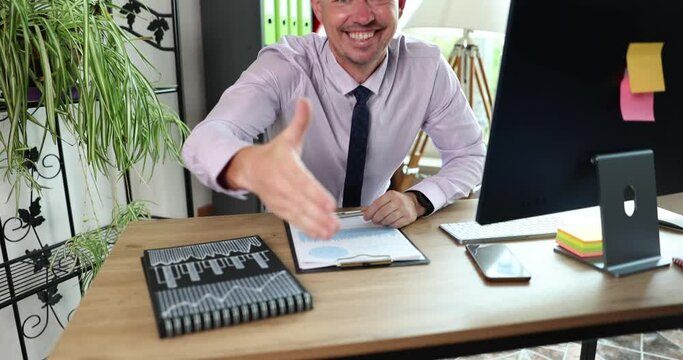 Recruitment agent male recruiter sits at table and extends hand to camera for handshake