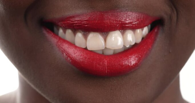 Close up view of a black woman with red lipstick blowing a kiss then smiling. Isolated on a white background.