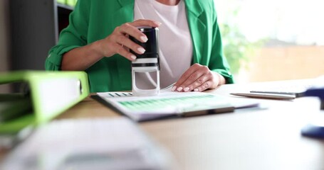 Woman at desk puts stamp on financial documents