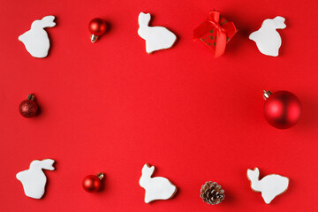 Delicious gingerbread in the form of a rabbit and Christmas decor on a red background. copy space. Symbol 2023