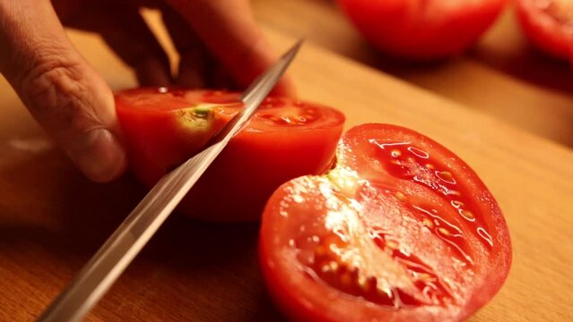Rozpołowienie pomidora oraz wycięcie szypułki z jednej połówki na drewnianej desce