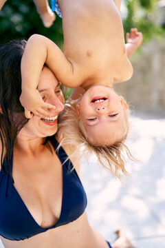 Laughing mother lifts a little girl hanging upside down by her legs. High quality photo