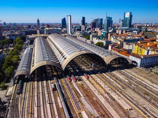 Deurstickers Aerial view of the station where trains arrive. An old arched structure made of metal and glass above the station poles. Tourism. Transport. Skyline with tall buildings. Italy, Milan, 09.2022 © VILTVART